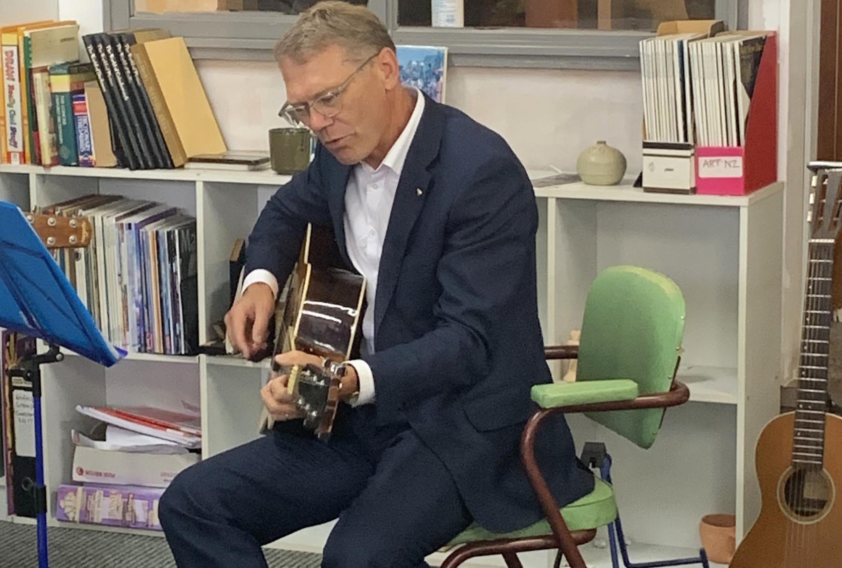 Arts Minister Paul Goldsmith plays a guitar at Artsenta